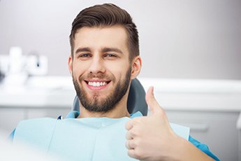 man in the dental chair giving a thumbs-up 