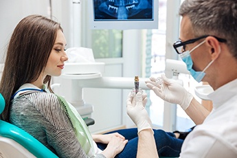 dentist showing a model of a dental implant to a patient 