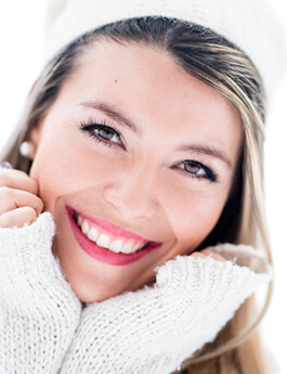 Woman wearing a white hat and a white sweater smiling
