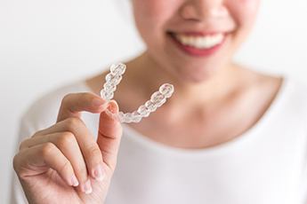 Woman holding aligner for Invisalign in Manchester Center, VT