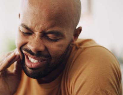 a man holding his cheek due tooth pain