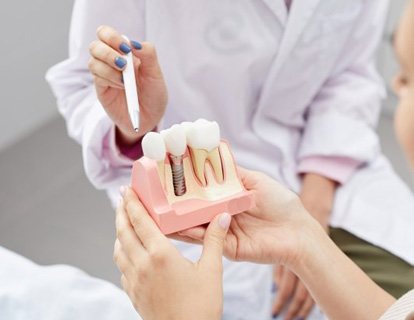 a patient holding a model of a dental implant