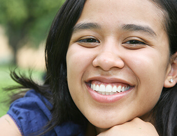 Young lady with dark hair and brown eyes showing her smile