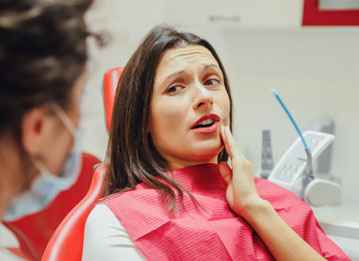 person holding their mouth in pain and talking to a dentist