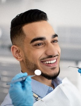 Man smiling at dentist while they examine his teeth