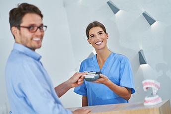 Smiling patient using credit card to pay for treatment