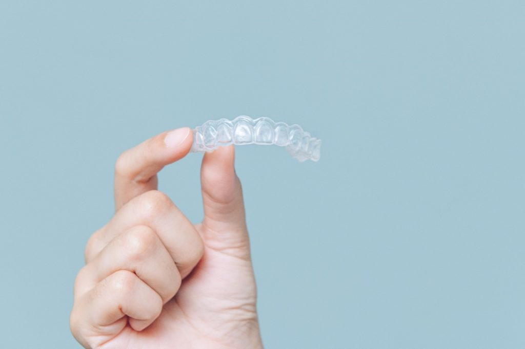 Person holding an Invisalign clear aligner.