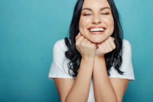 a woman smiling happily after removing an object that was stuck between her teeth